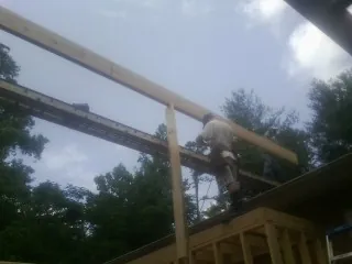 Carpenter setting a ridge beam over a new addition frame — Ice Dam Removal by Roofing Brothers in Mackey
