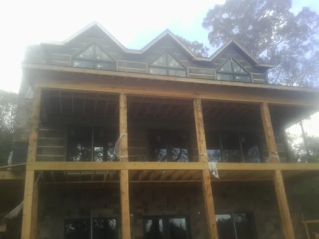 Dormers and porch framing on a large log home under construction — Roof Coating work by our crew in Mackey