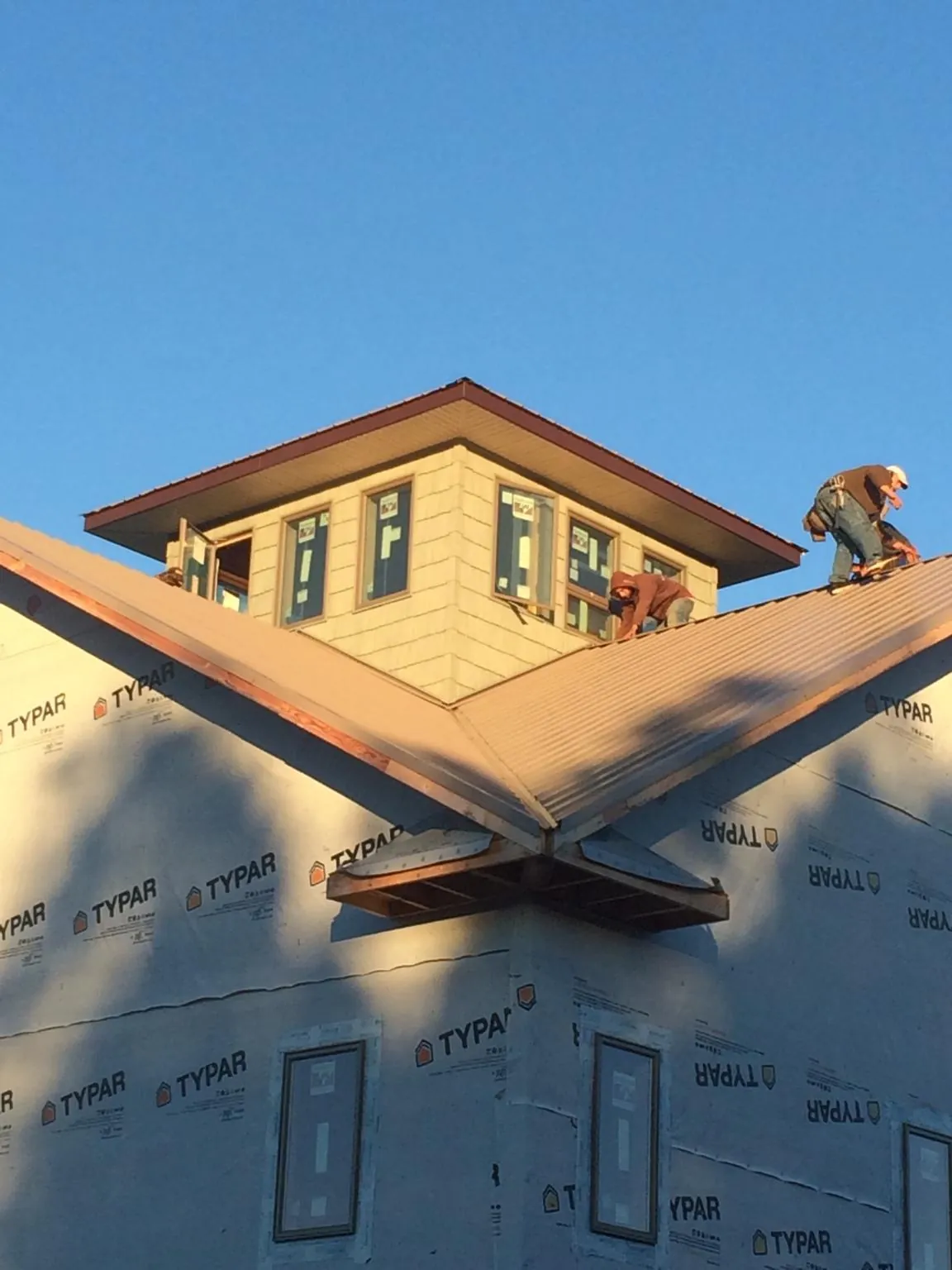 Roofers working around a rooftop cupola on a new metal roof at sunset — Roof Waterproofing in Mackey by Roofing Brothers